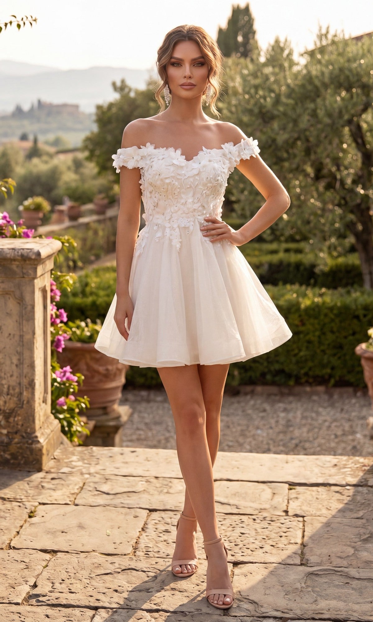 A woman stands outdoors in a garden setting, wearing the Chicas C312 Short Homecoming Dress in off white—a fit-and-flare, off-the-shoulder style adorned with 3D floral appliques—paired with nude heels as she poses on a stone pathway.